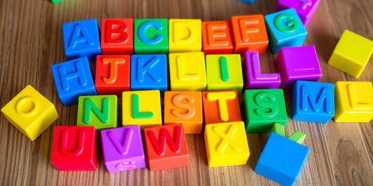 Colorful alphabet building blocks on a wooden surface.